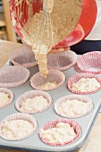 Putting muffin mixture into paper cases