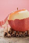 Apple, partly peeled, on cinnamon sticks