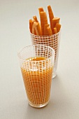 A glass of carrot juice and a glass of carrot sticks