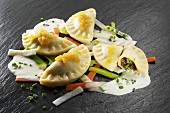 Potato ravioli on julienne vegetables with chive sauce