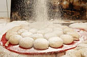 Dusting unbaked bread rolls with flour in bakery