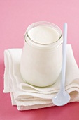 Jar of yoghurt and plastic spoon on cloth