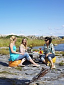 Drei Freundinnen beim Picknick am Meer