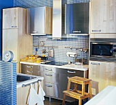 Küche mit blauen Mosaikfliesen, Edelstahl- und Holzfronten