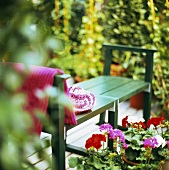 Garden bench with straw hat and geraniums