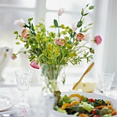 Flowers and bowl of salad on laid table