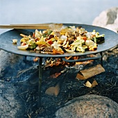 Meat and vegetables in wok on open fire