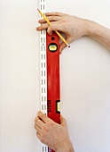 Hand holding a spirit level against the wall