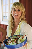 Blond woman holding dish of marinated fish