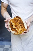 Baker holding freshly baked bread (Sweden)