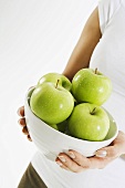 Woman holding bowl of fresh green apples