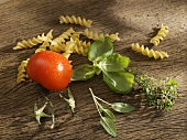 Fusilli, tomato and herbs on wooden board