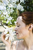 Young woman smelling white blossom