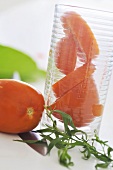 Whole and sliced tomato in glass, sprig of tarragon