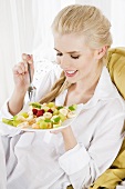 Blond woman eating fruit salad