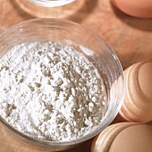 Flour in glass bowl, eggs beside it