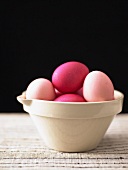 Coloured eggs in ceramic bowl