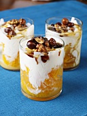 Fruit dessert with cream and nuts in glasses