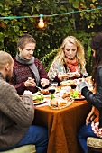 Family eating grilled sausages in a garden