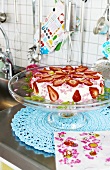 Strawberry gateau on cake stand in kitchen