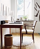 Ruhige Arbeitszimmerecke mit einfachem Arbeitstisch und gepolstertem Stuhl; ein Lammfell sorgt für warme Füsse