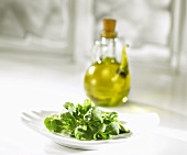 Feldsalat auf einem Teller mit Olivenöl im Hintergrund