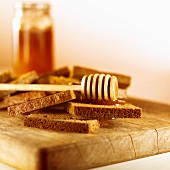 Wholemeal bread with honey and honey dipper on a board