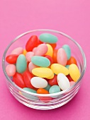 Coloured sugar eggs in glass dish, pink background