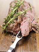 Roast saddle of venison with rosemary, piece on meat fork