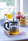 Teekanne, Toastbrot & Orangensaft auf einem Frühstückstisch