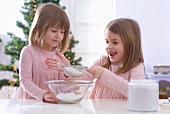 Christmas baking: two girls sieving icing sugar