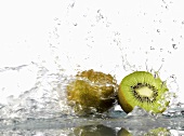 Whole and half kiwi fruit with splashing water