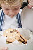 Boy looking at chocolate chip cookie in biscuit tin