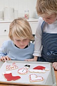 Two boys looking at Christmas biscuits on baking tray