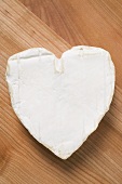 Heart-shaped Camembert on wooden background