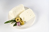 Sheep's cheese with olive and clove of garlic on plate
