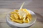 Pommes frites mit Mayonnaise und Plastikgabel auf Teller