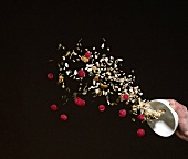 Hand throwing muesli with raspberries out of bowl