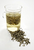 A glass of white tea and dried tea leaves