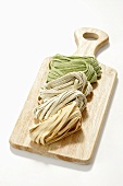 Chilli-, sage- and spinach fettuccine on wooden board