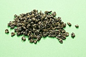 Green tea (dried tea leaves) on green background