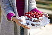 Woman holding a glass bowl of raspberry trifle