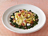 Tortellini with boiled egg and diced bacon on spinach