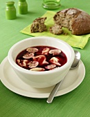 Clear beetroot soup with tortellini and button mushrooms