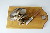 Oyster mushrooms with knife on wooden board