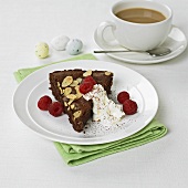 A piece of chocolate cake with cream and raspberries