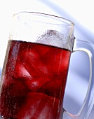 Red fruit juice with ice cubes in a glass tankard