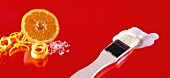 Fondant icing with pastry brush and orange against red background