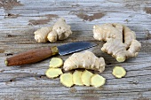 Ginger, whole and sliced, beside knife
