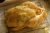 A stuffed oven-ready chicken on a rack